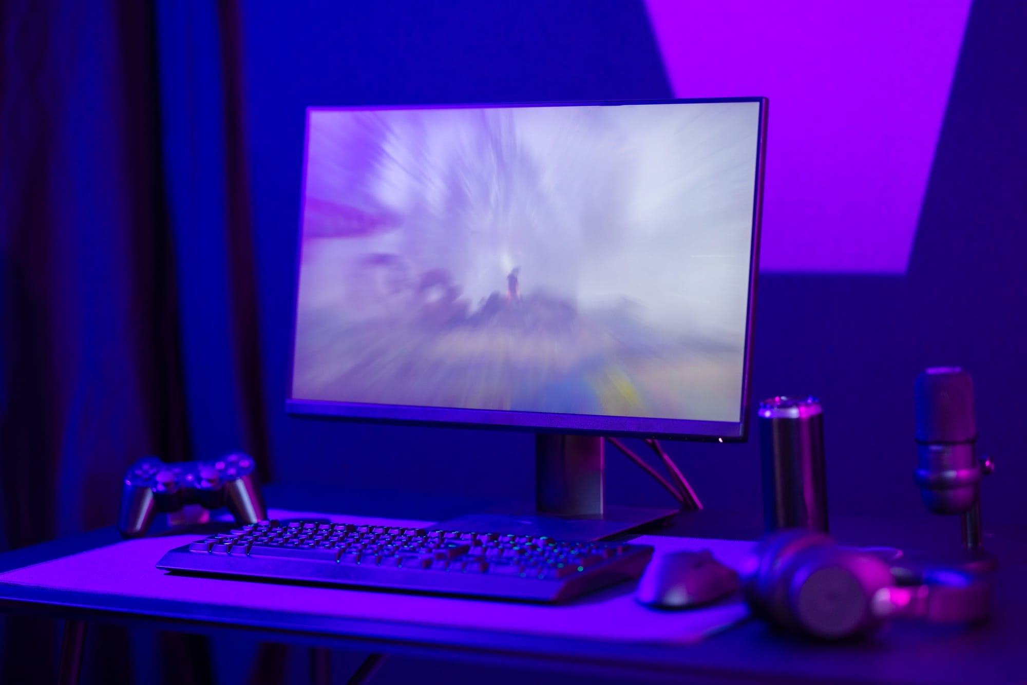 Modern gaming setup with controller, keyboard, and mic in purple lighting